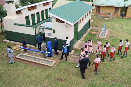 Aerial photography: School children and their teachers walking towards a sanitation facility