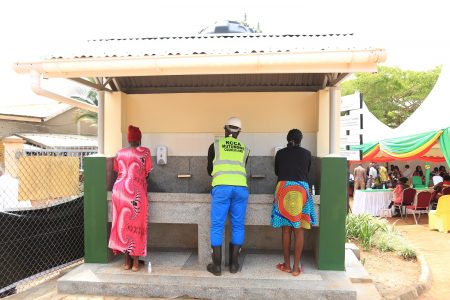 Three people washing hands and standing with their backs to the camera