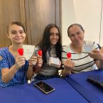 Three women holding up a menstruation cup