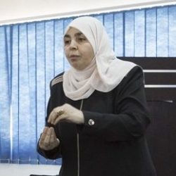 Eine muslimische Frau steht auf einer Bühne und erklärt etwas